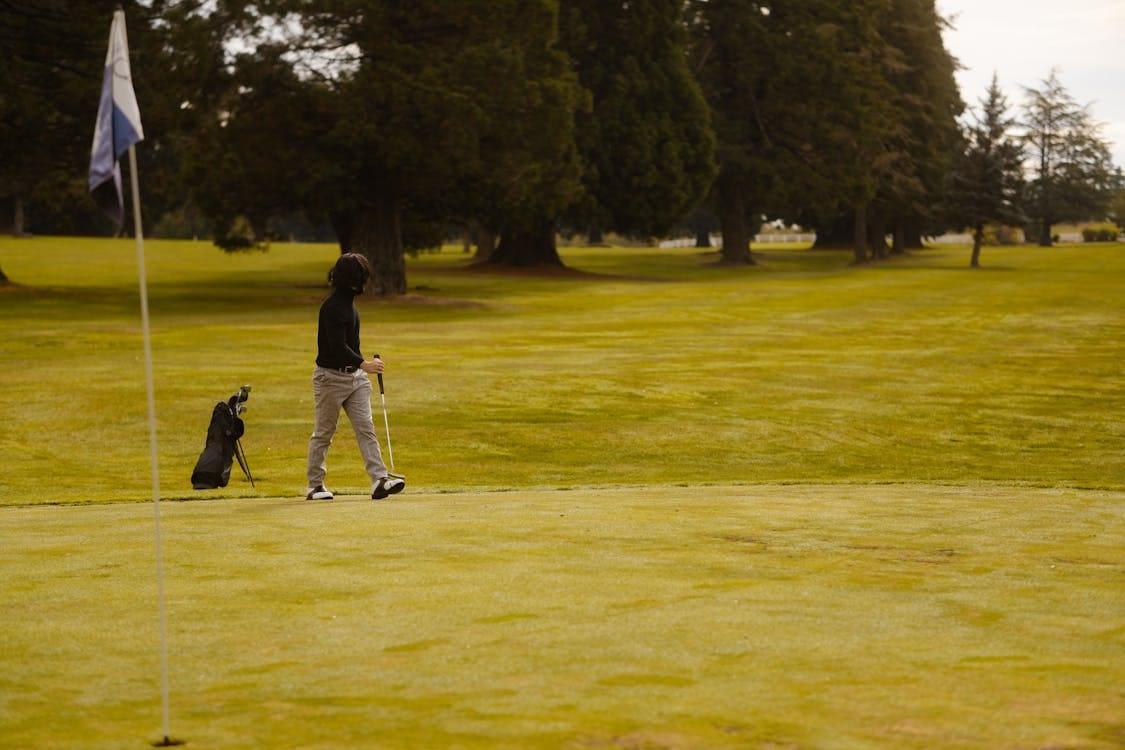 Golfeur marchant avec son sac de clubs sur un parcours verdoyant