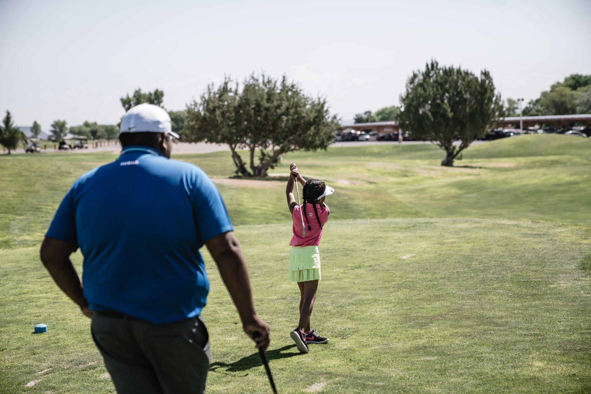 Jeune golfeuse s'entraînant sur le practice sous le regard de son moniteur