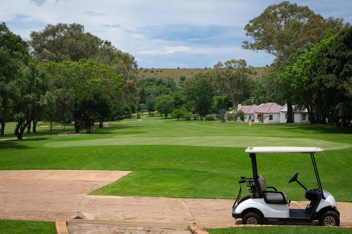 Voiturette de golf sur un parcours verdoyant sous un ciel bleu